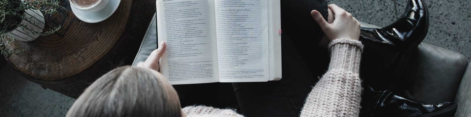 woman in white sweater reading book